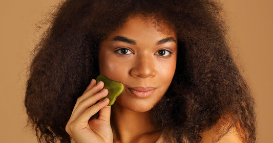 A woman with curly hair and caramel skin tone is holding a green soap bar, emphasizing her skincare routine.